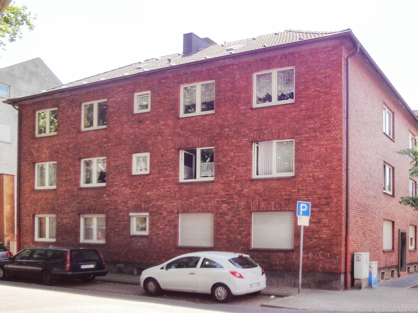 Immobilienmakler und Hausverwaltung Oberhausen - Bild eines Mehrfamilienhauses in Oberhausen, an einer Kreuzung, über Ecke aufgenommen mit roten Ziegel.